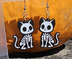 Are you obsessed with cats and the spooky season? Then it would be best to have these handmade Halloween goth skeleton cat earrings in your jewelry collection, stat. * Acrylic skeleton cat design * Lightweight and comfortable to wear * Unique, one-of-a-kind accessory * Perfect for Halloween and beyond These are made with black acrylic and painted white. The hooks are made of stainless steel that comes with a silicon backing. They are 1.14 inches wide and 1.59 inches tall Black Acrylics, Cat Earrings, Acrylic Earrings, Cat Design, White Painting, Skeleton, Jewelry Earrings Dangle, Jewelry Collection, Etsy Earrings