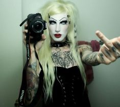 a woman with white makeup holding up a camera