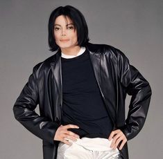 michael jackson is standing with his hands on his hips wearing white pants and a black jacket