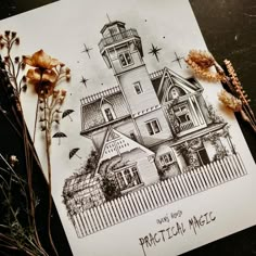 a drawing of a house on top of a piece of paper next to dried flowers