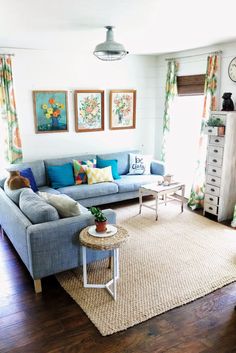 a living room with blue couches and pictures on the wall above it's coffee table