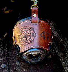 a fireman's helmet hanging from a leather keychain on a wooden table