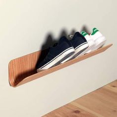 two pairs of shoes are sitting on a wooden shoe rack in the corner of a room