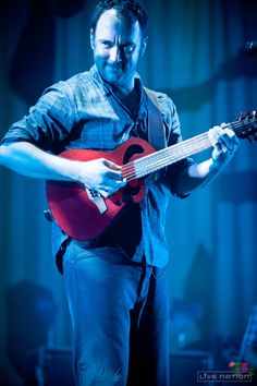 a man holding a red guitar on stage