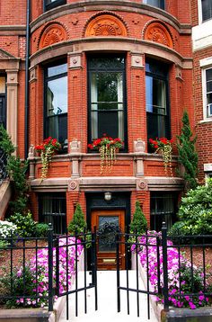 an old brick building with lots of flowers in front