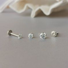 three pairs of diamond stud earrings on a table