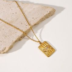 Inspired by ancient symbolism, the Egyptian Eye Necklace, in 18k gold plating, is a captivating accessory. Its intricate design symbolizes protection and wisdom, adding a touch of historical mystique to your fashion ensemble. Antique Gold Necklace With Rectangular Pendant, Engraved Gold Plated Amulet Charm Necklace, Elegant Tarnish-resistant Bronze Necklace, Gold Symbolic Square Pendant Jewelry, Spiritual Gold Jewelry With Rectangular Pendant, Symbolic Gold Square Pendant Jewelry, Symbolic Gold Jewelry With Square Pendant, Brass Amulet Necklace, Tarnish Resistant Bronze Pendant Necklace