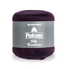 the yarn ball is dark purple and has white lettering on it that says patons silk bamboo