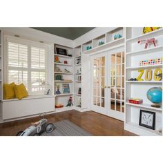 a room with lots of white bookcases and shelves filled with books on top of them