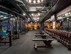 an empty gym with rows of benches and mirrors on the wall, all lit up by lights