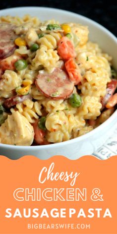 a white bowl filled with pasta and vegetables on top of a black table next to an orange sign that says cheesy chicken and sausage pasta