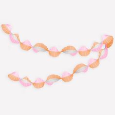 two seashells are hanging on a string against a white background, one is pink and the other is orange