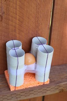 two vases sitting on top of a wooden table next to an egg in a carton