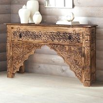 an ornate wooden table with two vases on it and a mirror in the corner