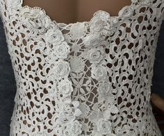 the back of a white lace dress with flowers on it