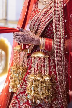 a woman in a red and gold bridal outfit with jewelry on her hand,