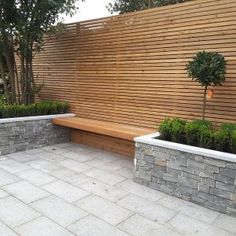 a wooden fence with two planters next to it and a bench in the middle