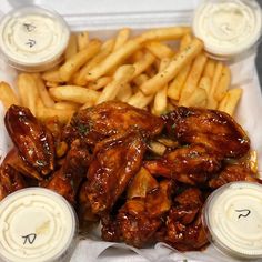 chicken wings, french fries and ketchup in containers on a white tablecloth