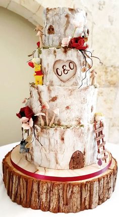 a three tiered wedding cake on top of a tree stump with hearts and flowers