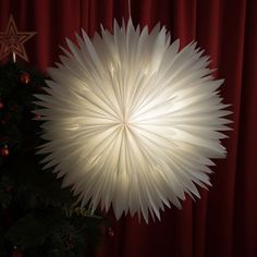 a large white paper ball hanging from the ceiling next to a christmas tree with decorations on it