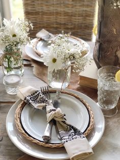 the table is set with plates, silverware and vases filled with white flowers