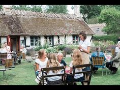 a group of people sitting on top of wooden chairs in front of a thatched roof house