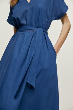 This blue summer midi dress is crafted in linen style fabric. It has short drop sleeves and a deep V neckline. There is a vertical seam in the front.  It has belt loops at the waist with a belt in the same fabric creating the perfect fit. The hem is slightly rounded. The dress is styled in a loose A line silhouette. Gentle machine wash. Turn garment inside out. Cold water. Mild detergent. Iron on reverse side. Do not tumble dry. Do not bleach. Summer Midi Dress, Belted Midi Dress, Busy Lifestyle, Linen Style, Midi Dress Summer, Professional Women, Mens Jewelry Bracelet, Dress C, Independent Designers Fashion