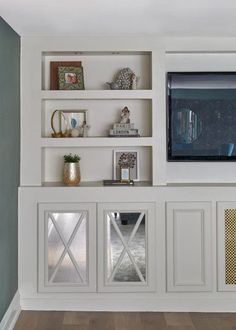 an entertainment center with white shelves and glass doors