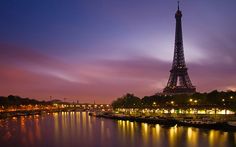 the eiffel tower lit up at night with boats in the water around it