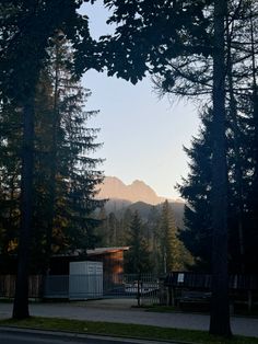 the sun shines on some trees and mountains in the distance, with a small cabin behind them