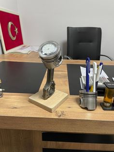 a desk with a clock, pen holder and other office supplies on top of it