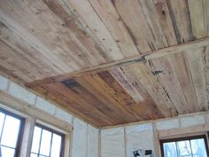 wood paneling on the ceiling in a room with windows and wooden flooring,