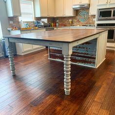 a kitchen island in the middle of a wooden floor