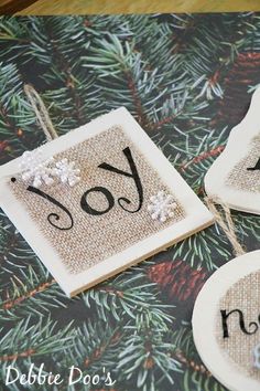 three christmas ornaments with the number one and two are hanging on a tablecloth that has pine needles