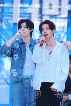 two young men standing next to each other holding microphones