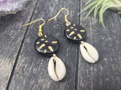 These gorgeous dangle earrings feature genuine off-white sliced moneta cowrie shells dangling beneath 20mm round carved black and gold acrylic beads an etched Afrocentric abstract pattern. Aching for acrylics? Check out the rest of my acrylic jewelry here: https://etsy.me/2IadiWZThroughout Africa and the Americas, cowrie shells have historically been viewed as symbols of womanhood, fertility, and prosperity. Check out my other cowrie shell jewelry here: https://etsy.me/2VQS0r0These earrings meas Black Drop Earrings For Summer, Black Dangle Jewelry For Beach, Artisan Black Jewelry For The Beach, Black Shell Jewelry For Gifts, Black Shell Jewelry Gift, Black Shell Jewelry As A Gift, Unique Black Beach Jewelry, Handmade Black Jewelry For Vacation, Black Shell Bohemian Jewelry