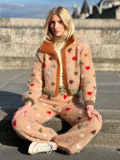 a woman is sitting on the ground wearing pajamas and a jacket with hearts all over it