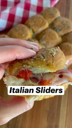 a person holding a sandwich in their hand with the words italian sliders above it