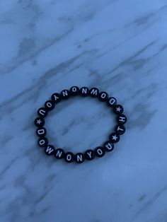 a black and white beaded bracelet with the word wonder written in cursive writing