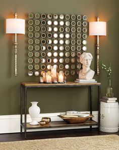 a table with candles and plates on it in front of a green wall decorated with mirrors