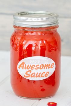 a jar filled with red liquid sitting on top of a white wooden table next to a candy bar