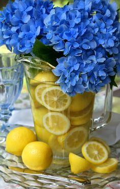 a pitcher filled with lemons and blue flowers