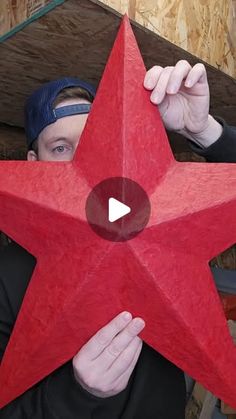 a man holding up a red star in front of his face