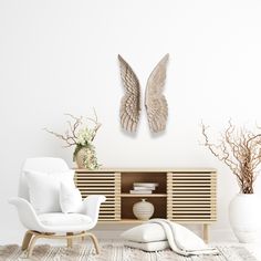 a living room with white furniture and two angel wings on the wall