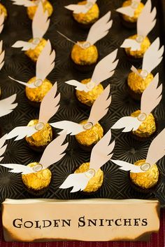 golden snitches are arranged on a black tray with white doves in the middle