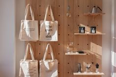 three totes hanging on the wall in front of shelves with books and other items