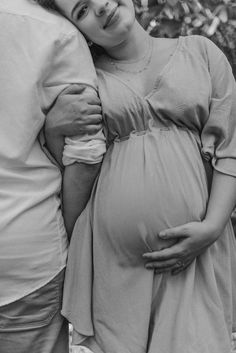 black and white photograph of a pregnant woman with her arm around the belly of a man