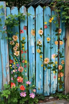 a fence with flowers painted on it and vines growing up against the blue wooden fence