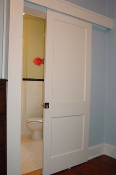 an open door leading to a bathroom with a toilet in the corner and wood floors