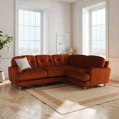 an orange sectional sofa in a white room with hardwood flooring and large windows on the wall